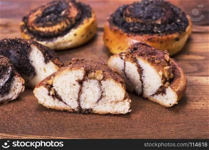 baked round buns with nuts and cinnamon, behind pastries with poppy seeds