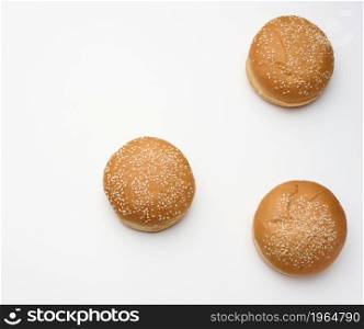 baked round fresh white wheat flour bun sprinkled with sesame seeds on a white table. Hamburger, cheeseberger and sandwich bun