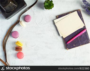 baked round macarons, notebook, pen and plants in a pot on a white background, top view, empty space