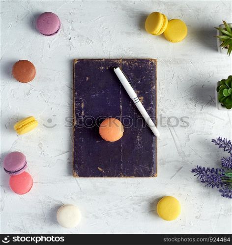 baked round macarons, notebook, pen and plants in a pot on a white background, top view