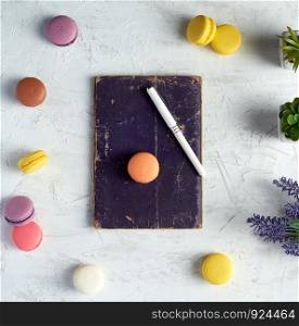 baked round macarons, notebook, pen and plants in a pot on a white background, top view