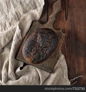 baked rye bread on a gray linen napkin, brown wooden table, top view