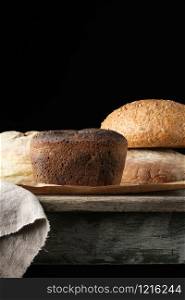 baked rye flour bread on a wooden table, dark background