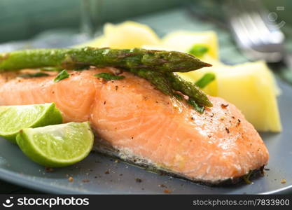 Baked salmon fillet with green asparagus, lime wedges and boiled potatoes (Selective Focus, Focus on the tip of the asparagus heads)