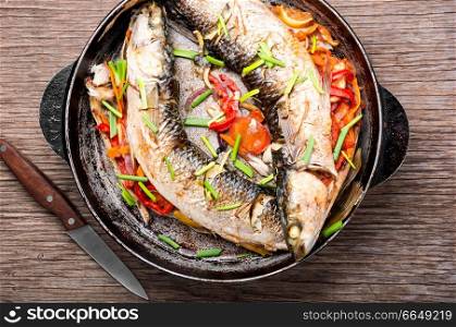 Baked sea fish stuffed with vegetables on vintage wooden table. Tasty baked whole fish