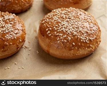 baked sesame buns on brown parchment paper, ingredient for a hamburger, close up
