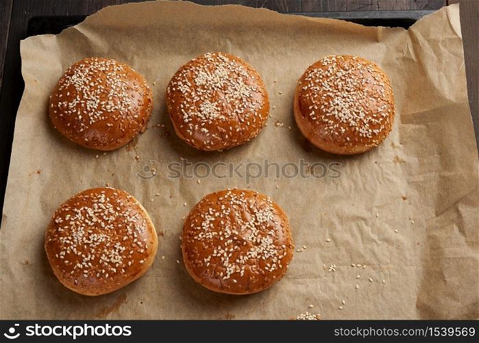 baked sesame buns on brown parchment paper, ingredient for a hamburger, top view