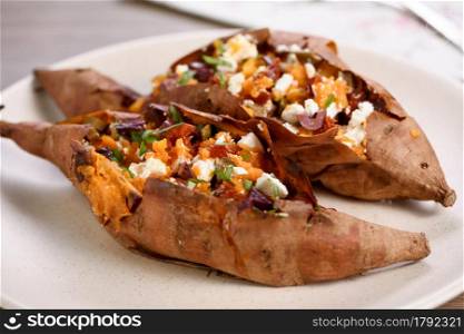 Baked sweet potato stuffed with chopped sun-dried tomatoes, olives, feta cheese and basil with aromatic dressing