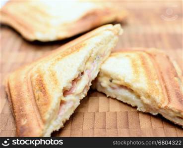Baked toast with ham and cheese on a wooden plate.