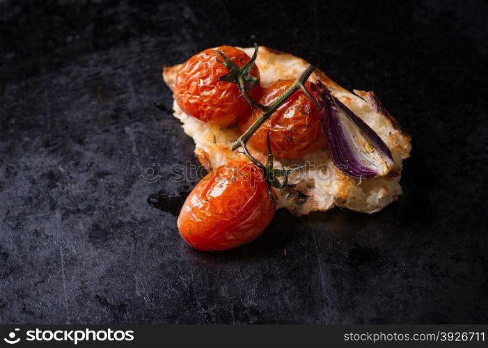 Baked tomatoes with toasted bread on dark background, selective focus, top view