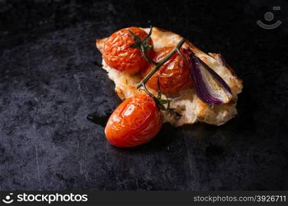 Baked tomatoes with toasted bread on dark background, selective focus, top view
