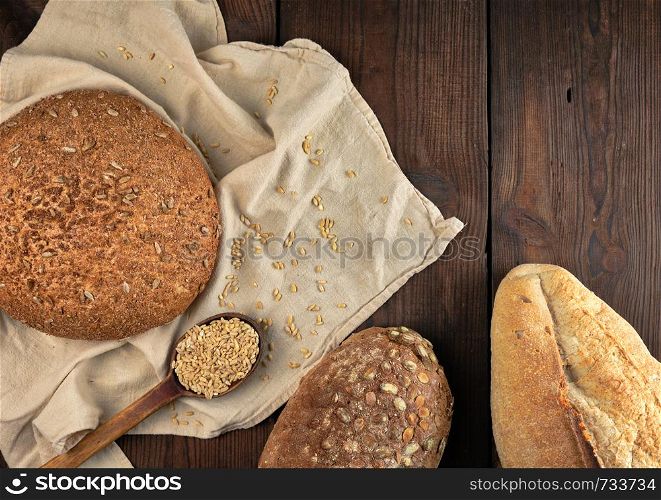baked various breads on a beige kitchen towel, wooden background, top view, copy space