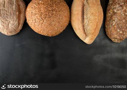 baked various loaves of bread on a black background, empty space, top view