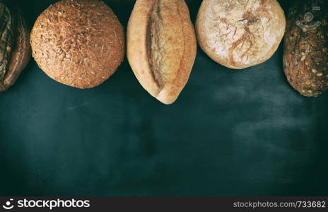 baked various loaves of bread on a black background, empty space , top view