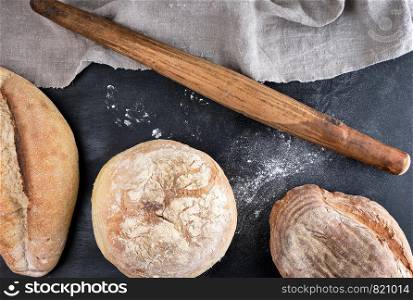 baked various loaves of bread on a black background, top view