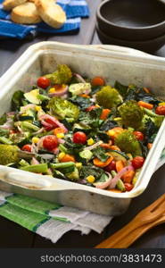 Baked vegetables (zucchini, onion, cherry tomato, broccoli, carrot, sweet corn, green bean, chard) seasoned with thyme in baking dish, photographed with natural light (Selective Focus, Focus one third into the image)