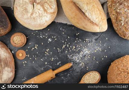 baked white wheat flour and rye with pumpkin seeds and sunflower on a black background, top view, copy space