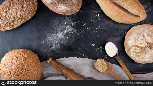 baked white wheat flour and rye with pumpkin seeds and sunflower on a black background, top view, copy space