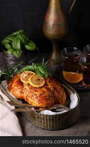 Baked whole chicken in spices with crispy appetizing fried crust in a tray, dark moody