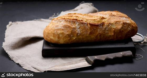 baked whole oval bread made from white wheat flour on a black table
