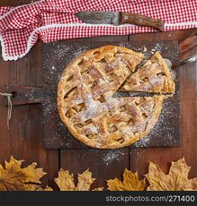 Baked whole round apple pie on a rectangular old brown board, wooden table, top view