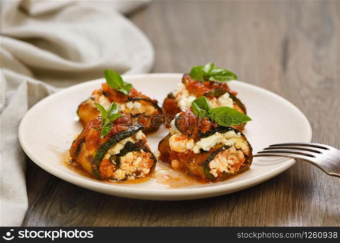Baked zucchini rolls stuffed with ricotta and basil under tomato-onion-carrot gravy