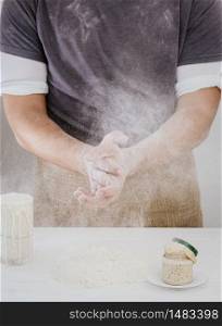Baker claps his hands with flour in the kitchen. Close-up, the process of making bread from natural sourdough at home. Hobbies during quarantine. Sourdough and flour on the table. Baker claps his hands with flour in the kitchen. Close-up, the process of making bread