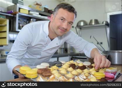 Baker holding tray of cakes