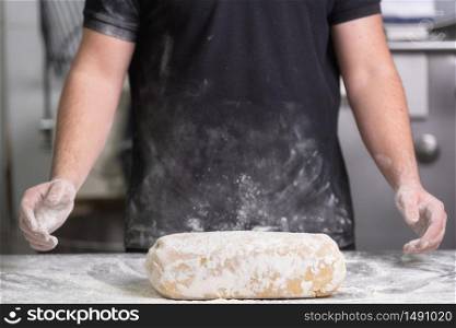 Baker kneading fresh raw bread dough at the bakery .. Baker kneading fresh raw bread dough at the bakery.