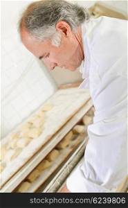 Baker preparing trays of bread rolls