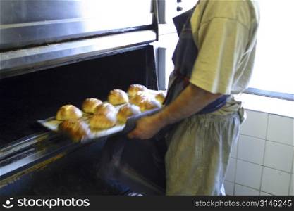 Baker removing bread from oven