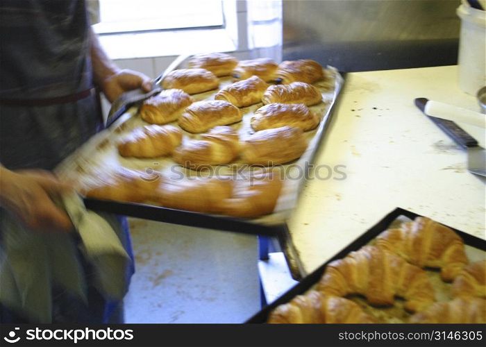 Baker removing croissants from oven