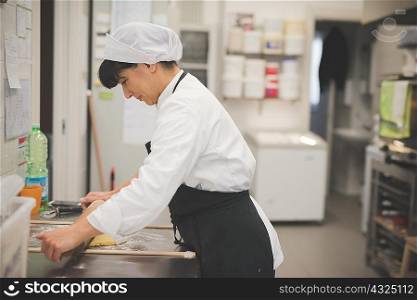 Baker rolling dough in kitchen