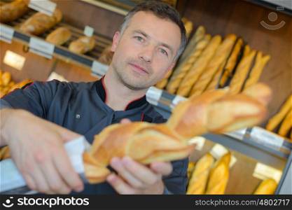 baker selling fresh bread baguettes in bakery