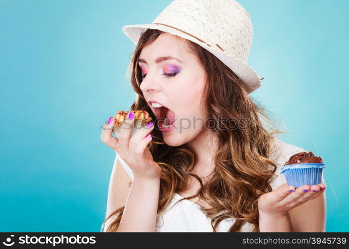 Bakery, sweet food and people concept. Closeup smiling summer woman curly hair straw hat holding cakes cupcakes in hands blue background
