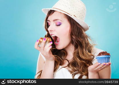 Bakery, sweet food and people concept. Closeup smiling summer woman curly hair straw hat holding cakes cupcakes in hands blue background