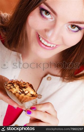 Bakery sweet food and people concept. Smiling woman holds cake cupcake in hand high angle view orange background