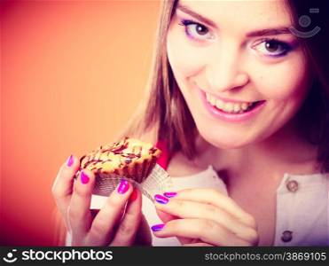 Bakery sweet food and people concept. Smiling woman holds cake cupcake in hand orange background