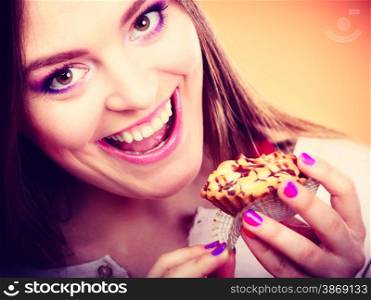 Bakery sweet food and people concept. Smiling woman holds cake cupcake in hand orange background