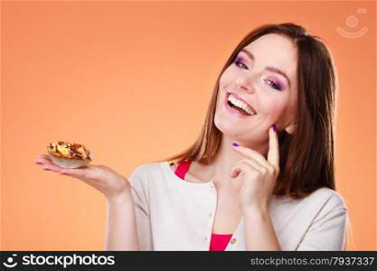 Bakery, sweet food and people concept. Smiling woman holds cake cupcake in hand orange background