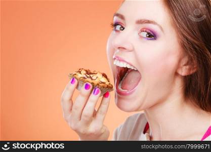 Bakery, sweet food and people concept. Woman wide open mouth holds cake cupcake in hand orange background