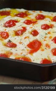 Baking a raw focaccia bread with fresh tomatoes