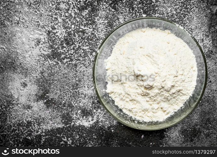 Baking background. Bowl of flour on a rustic background.. Bowl of flour on a rustic background.