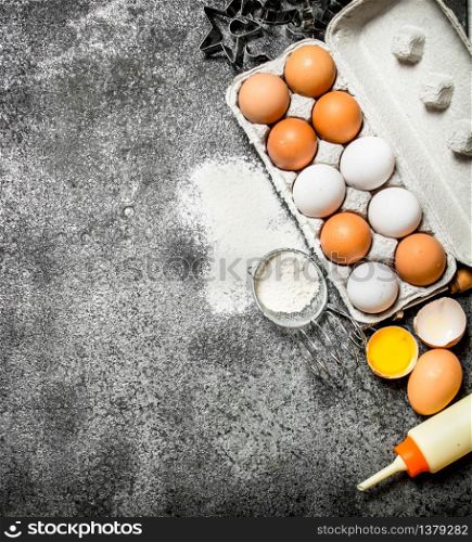 Baking background.Fresh eggs from the scattered flour. On rustic background. Baking background.Fresh eggs from the scattered flour.