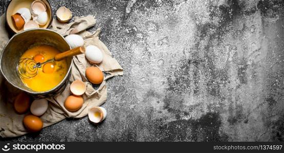 Baking background. Whisking eggs in the old bowl . On rustic background.. Baking background. Whisking eggs in the old bowl .