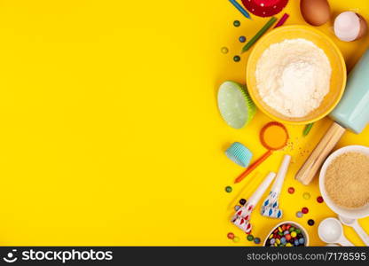 Baking birthday cupcakes background frame. Ingredients, kitchen items for baking, candles. Kitchen utensils, flour, eggs, sugar. Text space, top view.. Baking birthday cupcakes ingredients on yellow background, flat lay