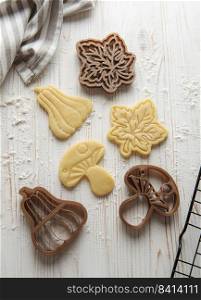 Baking cookies in the form of pumpkin and leaves. Cozy autumn pastry. Dough with cookie cutters.