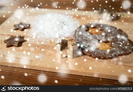 baking, cooking, christmas and food concept - close up of ginger dough, molds and flour on wooden cutting board from top