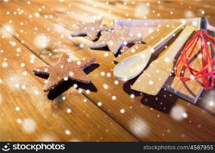 baking, cooking, christmas and food concept - close up of gingerbread cookies, kitchenware set and towel on wooden cutting board at home kitchen