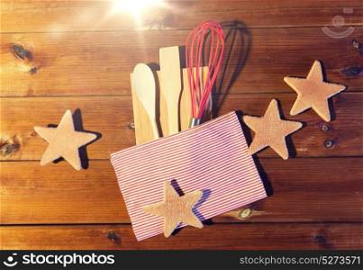 baking, cooking, christmas and food concept - close up of gingerbread cookies, kitchenware set and towel on wooden cutting board at home kitchen from top. close up of gingerbread and baking kitchenware set